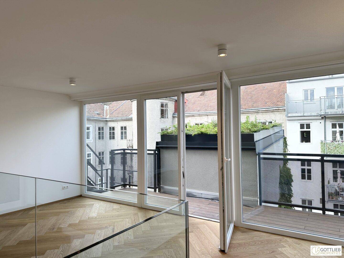 Lichtdurchfluteter Wohnbereich mit Fischgrätparkett und Zugang zu einer privaten Terrasse oder Balkon.