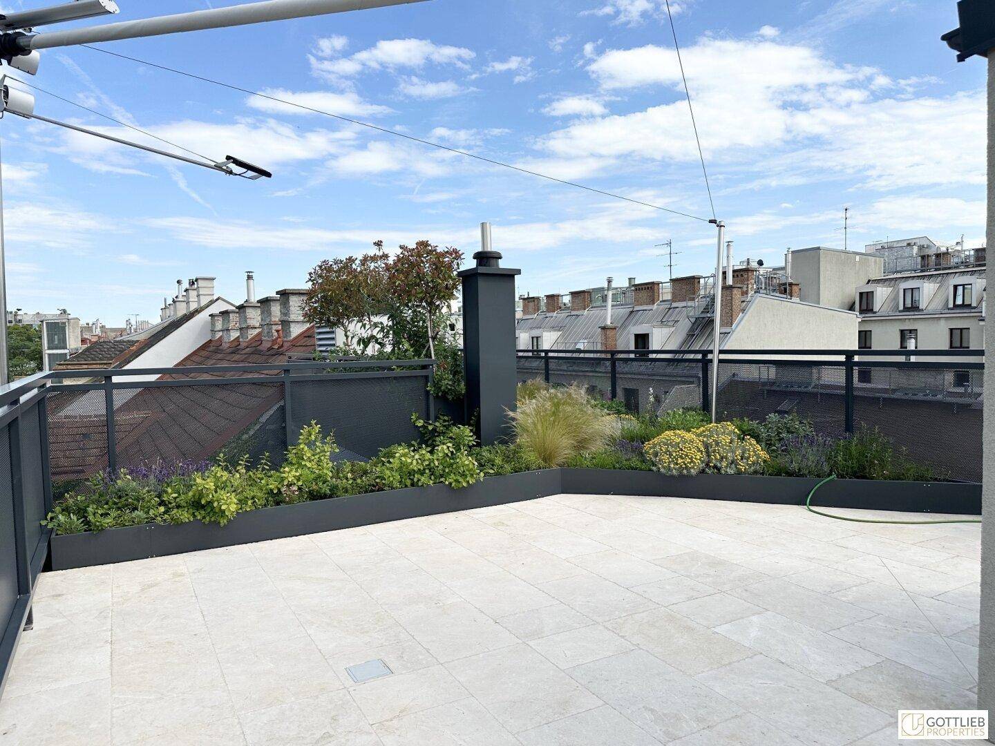 Weitläufige Dachterrasse mit modernen Pflanzbeeten und Panoramablick über die Stadt.