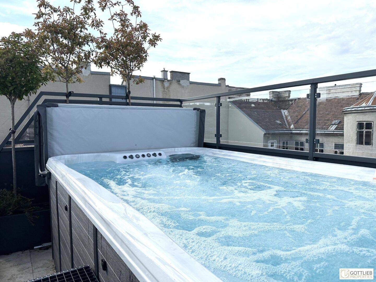 Exklusive Dachterrasse mit großem Whirlpool und Blick auf die städtische Umgebung.