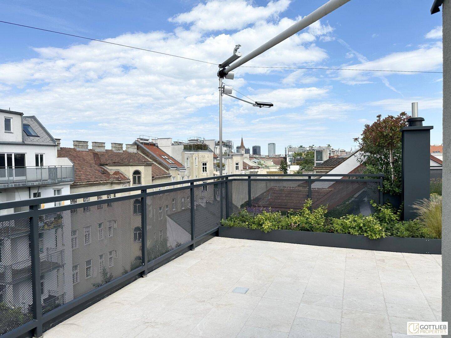 Geräumige Dachterrasse mit weitem Blick über die Dächer der Stadt und den Horizont.