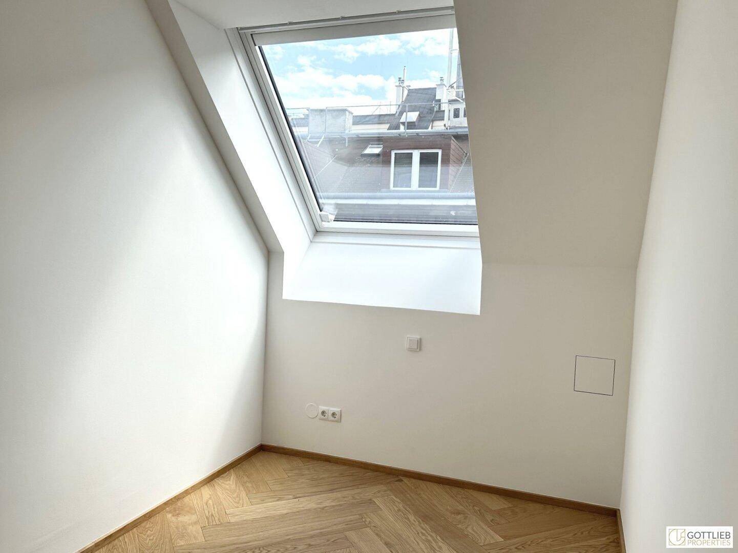Gemütliches Zimmer im Dachgeschoss mit viel Tageslicht durch das große Dachfenster.