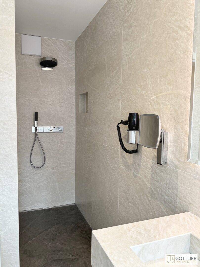 Elegantes Badezimmer mit begehbarer Dusche, modernen Armaturen und großformatigen Fliesen.