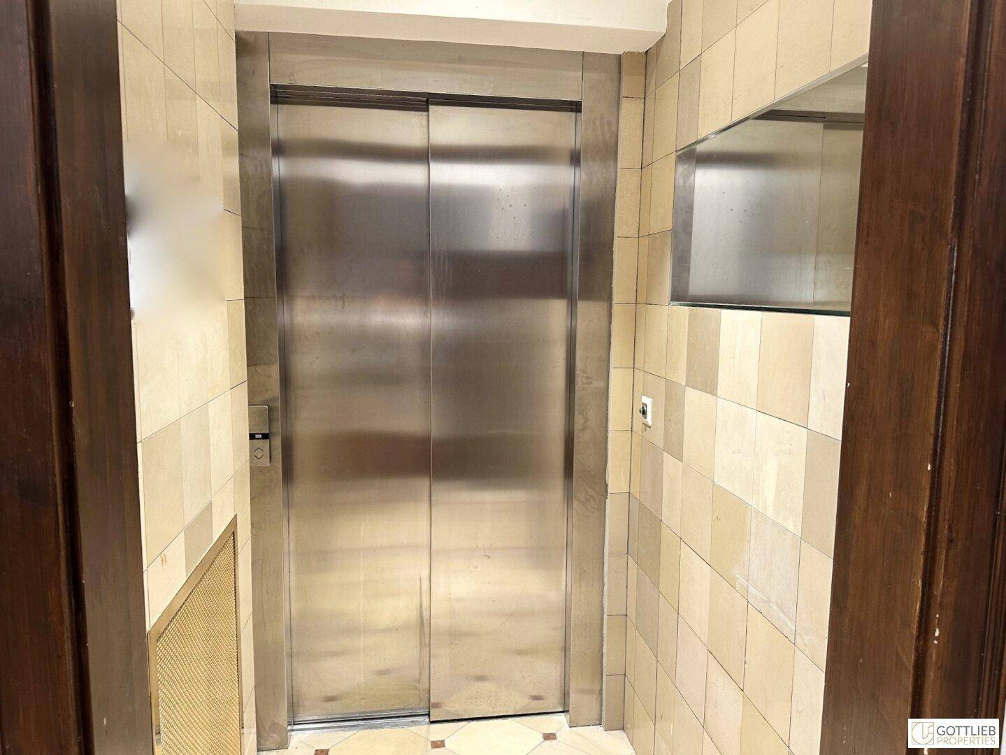 Eingangsbereich mit modernem Aufzug und gefliestem Boden.