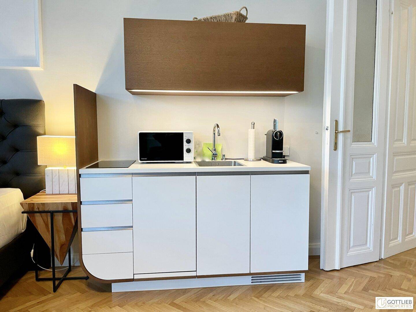 Detailansicht der modernen Küchenzeile mit Induktionskochfeld, Spüle und integrierter Mikrowelle.