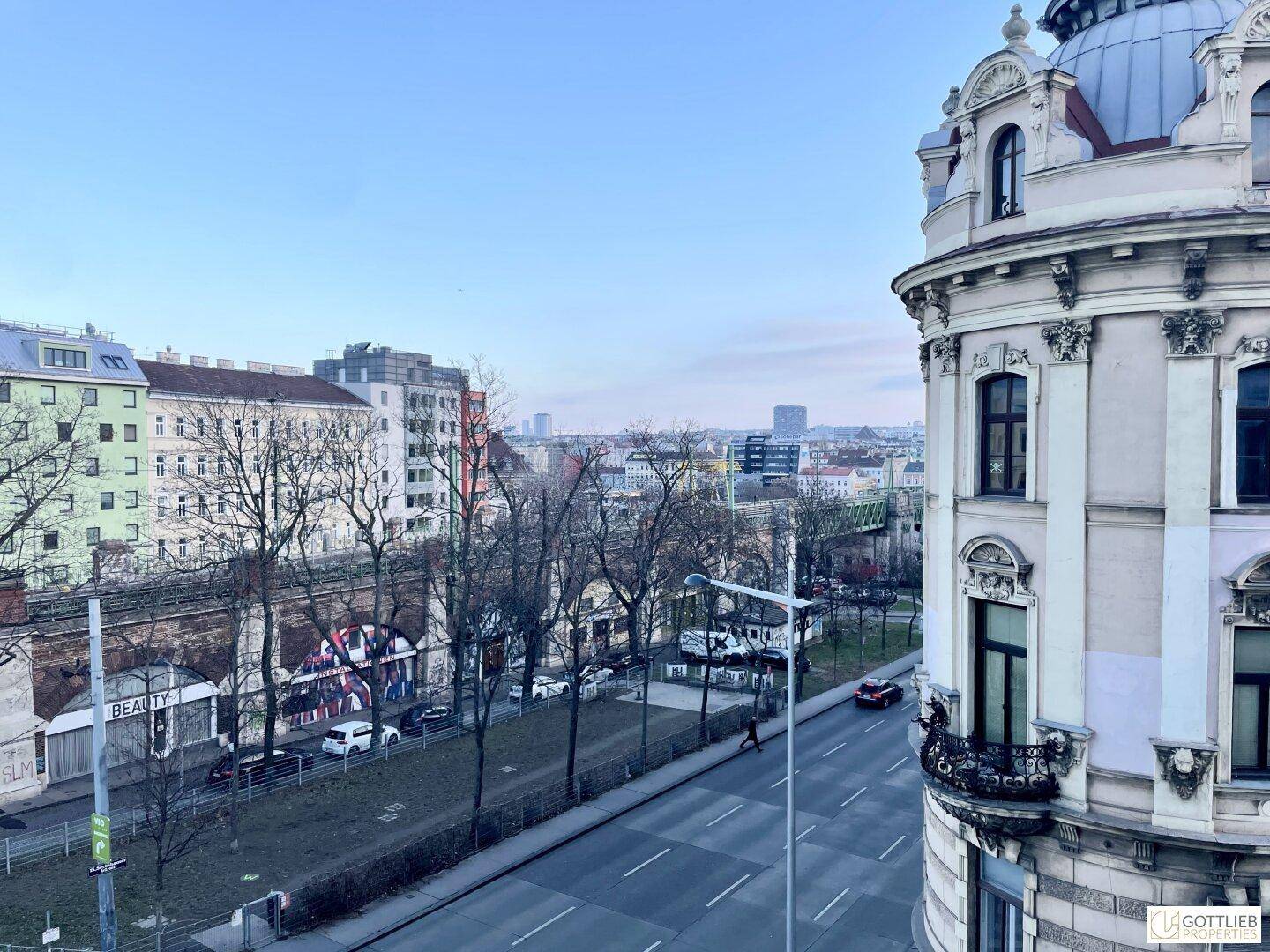Panoramablick über eine belebte Stadtstraße mit historischer Architektur und modernen Gebäuden unter hellem Himmel.