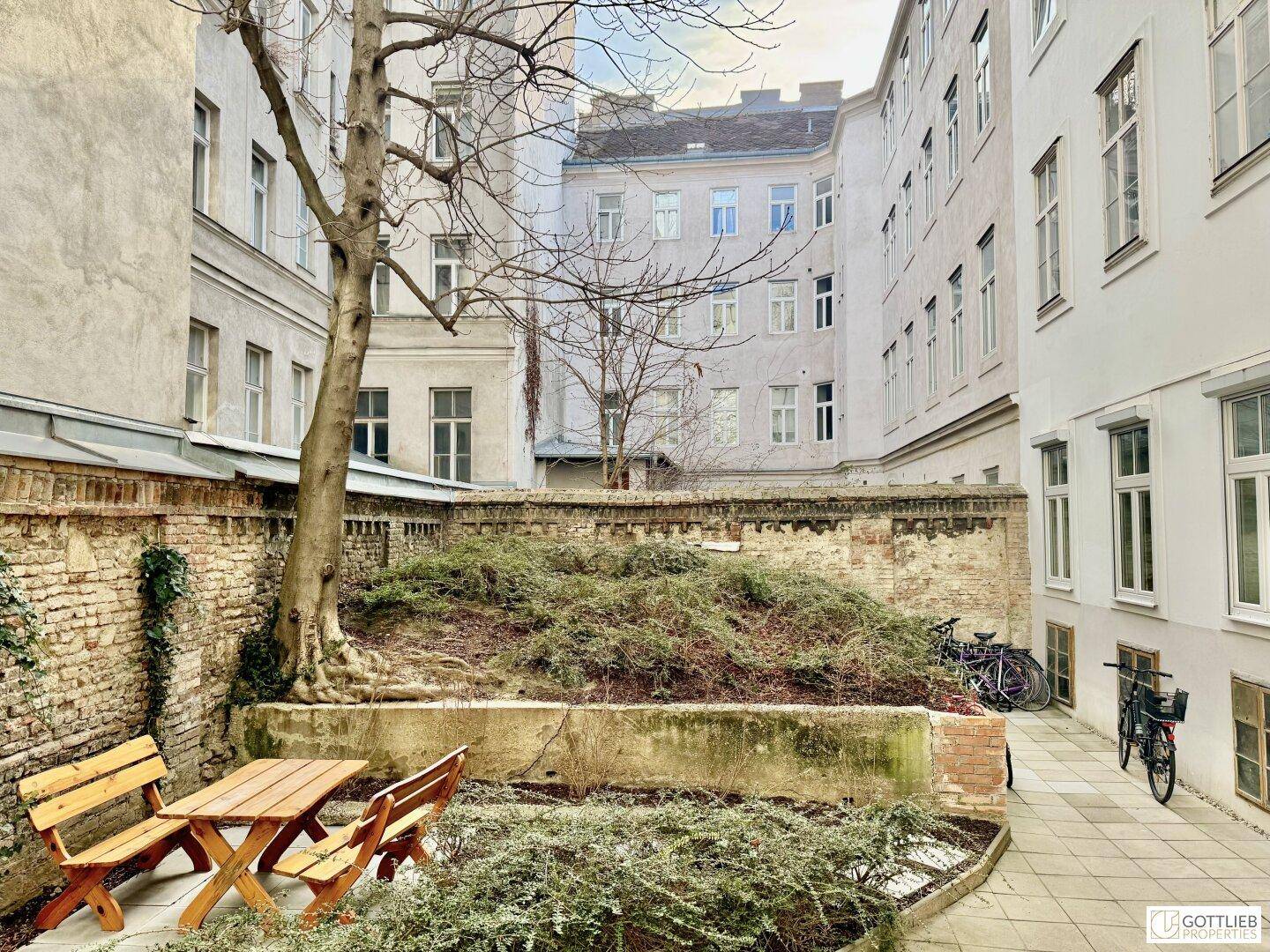 Begrünter Innenhof mit Sitzgelegenheiten, Bäumen und Fahrradstellplätzen.