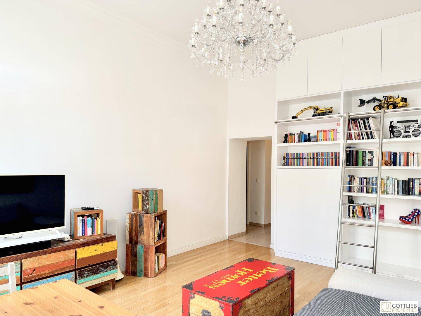 Geräumiges Wohnzimmer mit Einbauregalen, Leiter und Holzboden, ideal für Bücherliebhaber.