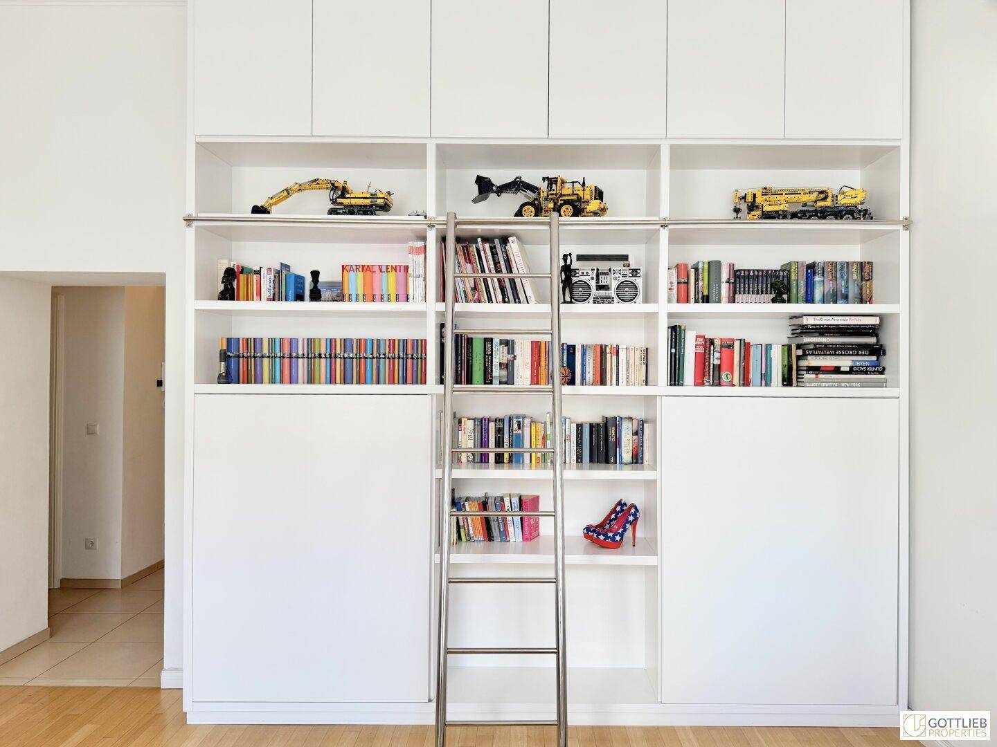 Große weiße Einbauregale mit Leiter und Stauraum, perfekt für Bücher und Dekoration.