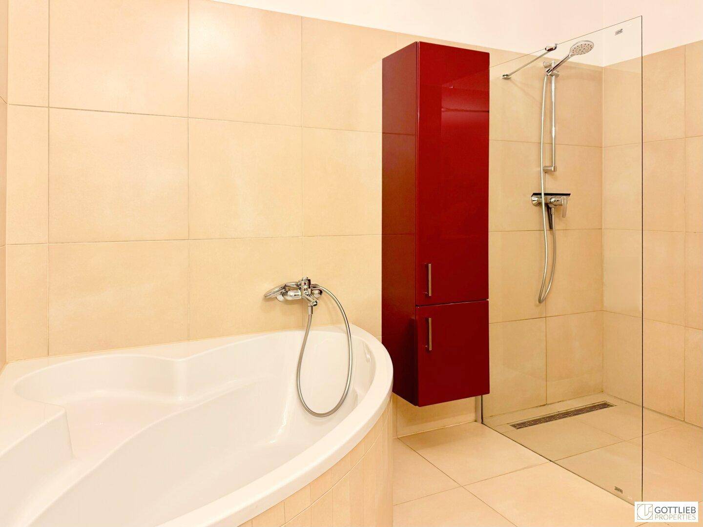 Badezimmer mit Eckbadewanne, begehbarer Dusche und rotem Hochschrank.