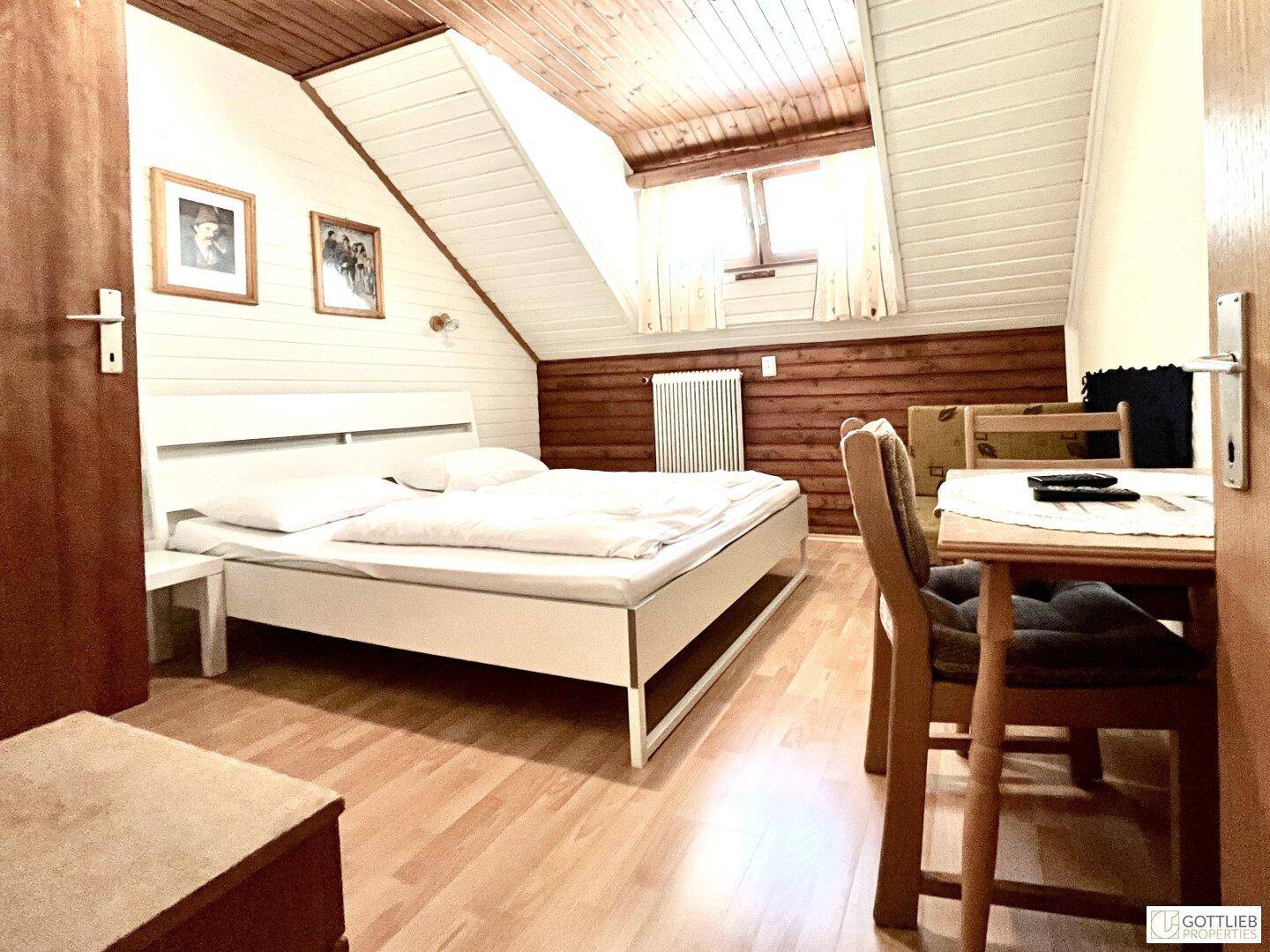 Helles Schlafzimmer mit Doppelbett, Holzboden und Dachschrägen, bietet eine gemütliche Atmosphäre.