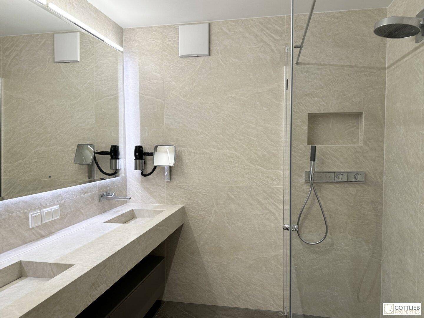 Modernes Badezimmer mit doppelten Waschbecken, begehbarer Dusche und eleganten Fliesen.
