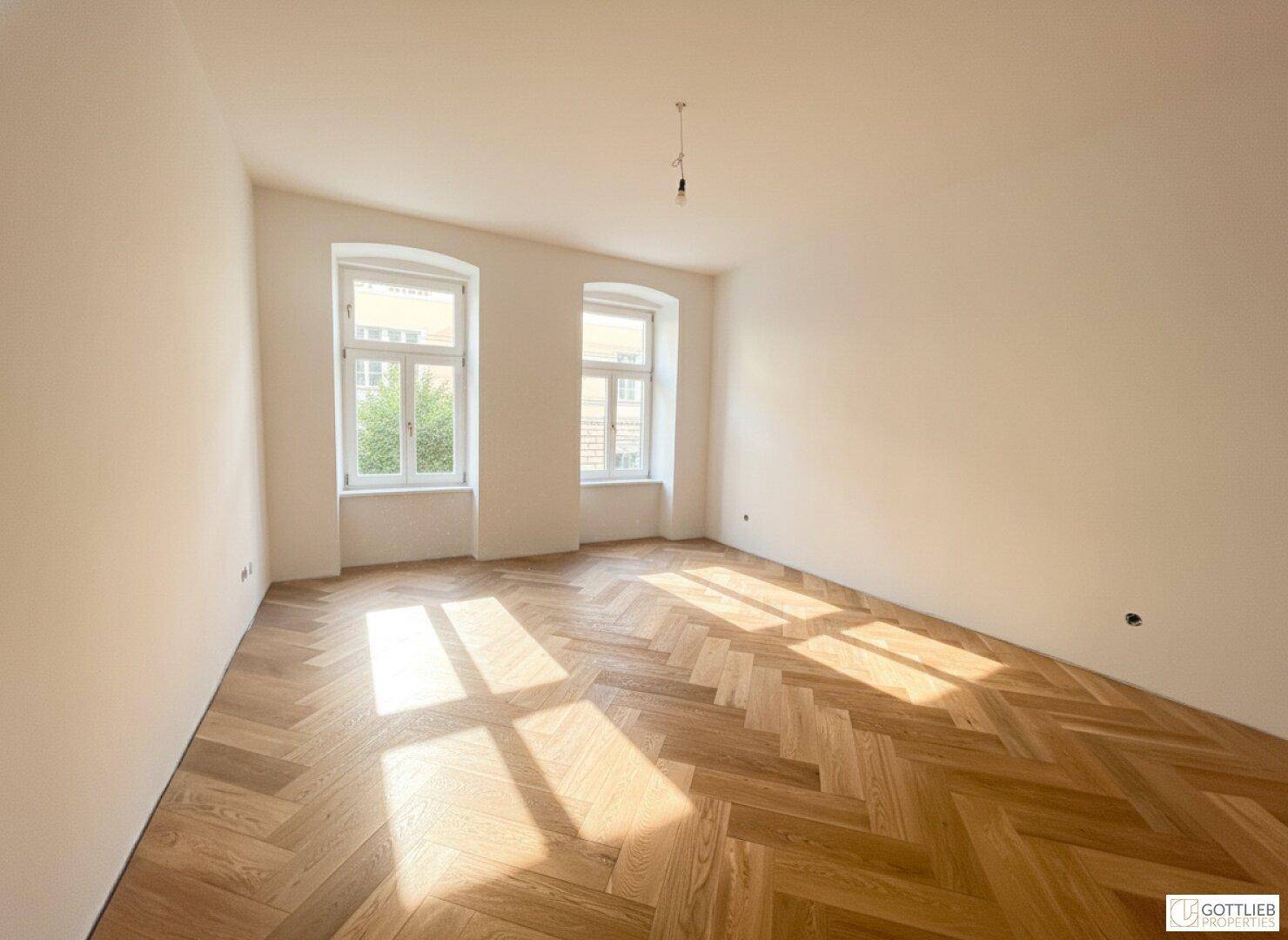 Geräumiges Zimmer mit elegantem Fischgrätparkett und viel natürlichem Lichteinfall.