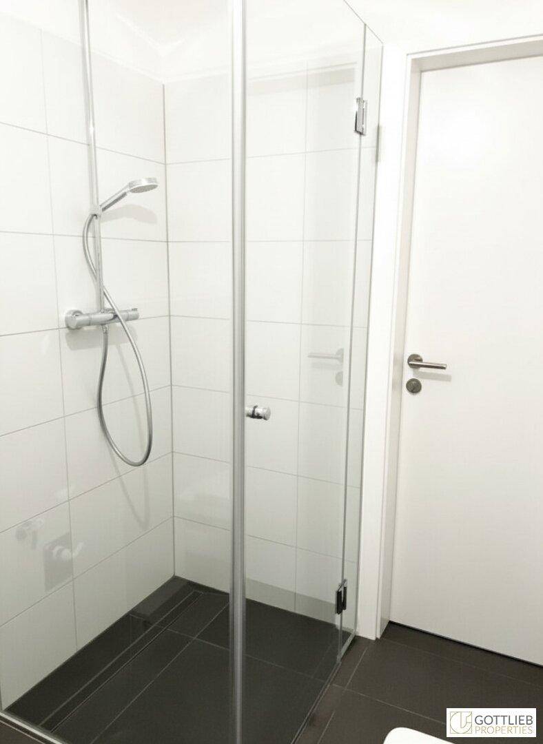 Elegantes Badezimmer mit ebenerdiger Dusche, Glasabtrennung und modernen Fliesen.