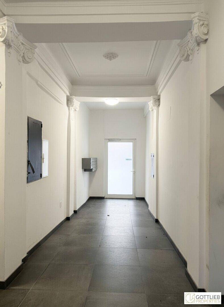 Langer, heller Flur im Eingangsbereich mit Stuckelementen an der Decke und Fliesenboden.