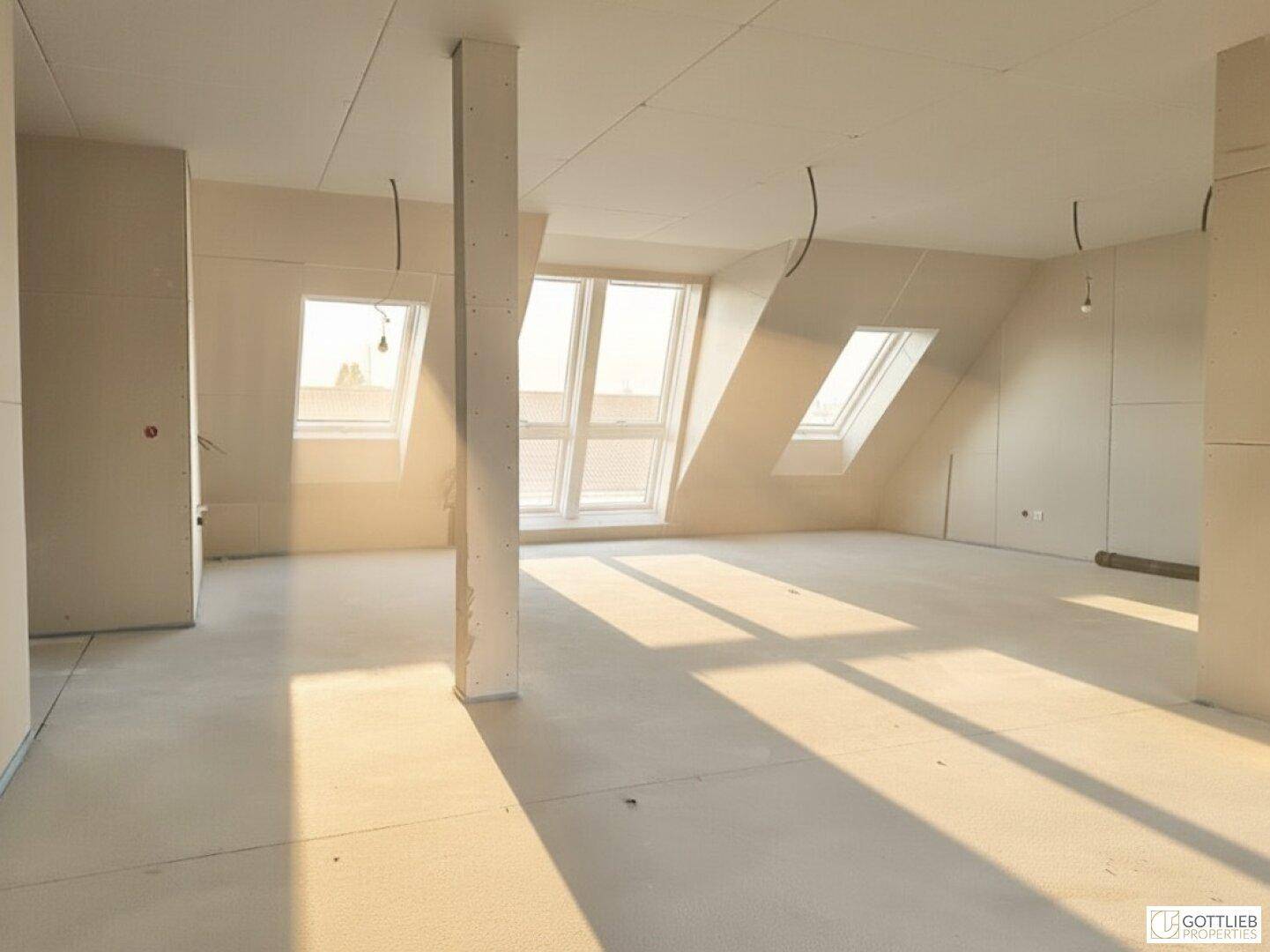 Großer Dachgeschossraum im Rohbau mit Stütze, schrägen Wänden und hellen Dachfenstern.