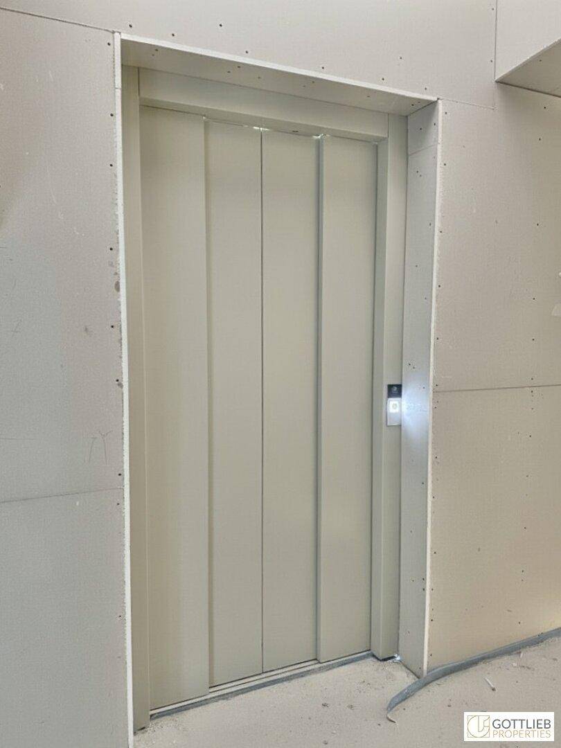 Aufzug in einem unfertigen Gebäude, umgeben von Trockenbauwänden.