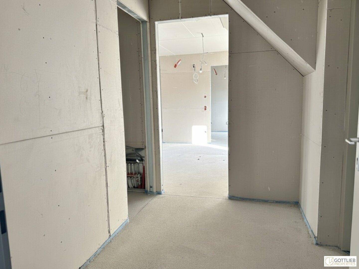 Unfertiger Innenraum mit Trockenbauwänden und Blick in weitere Räume während der Bauphase.
