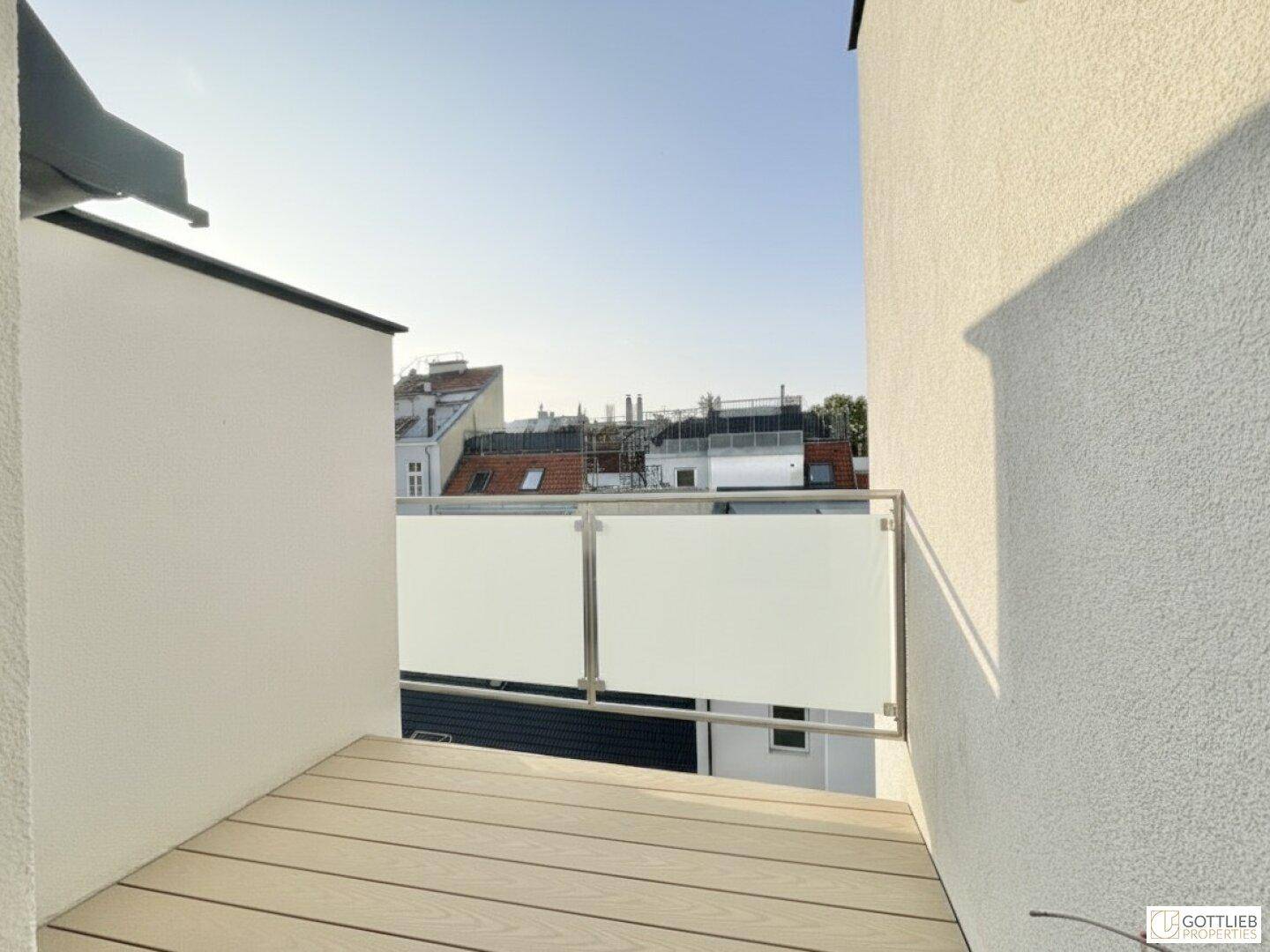 Kleiner Balkon mit Holzboden und Glasgeländer, bietet einen privaten Außenbereich.
