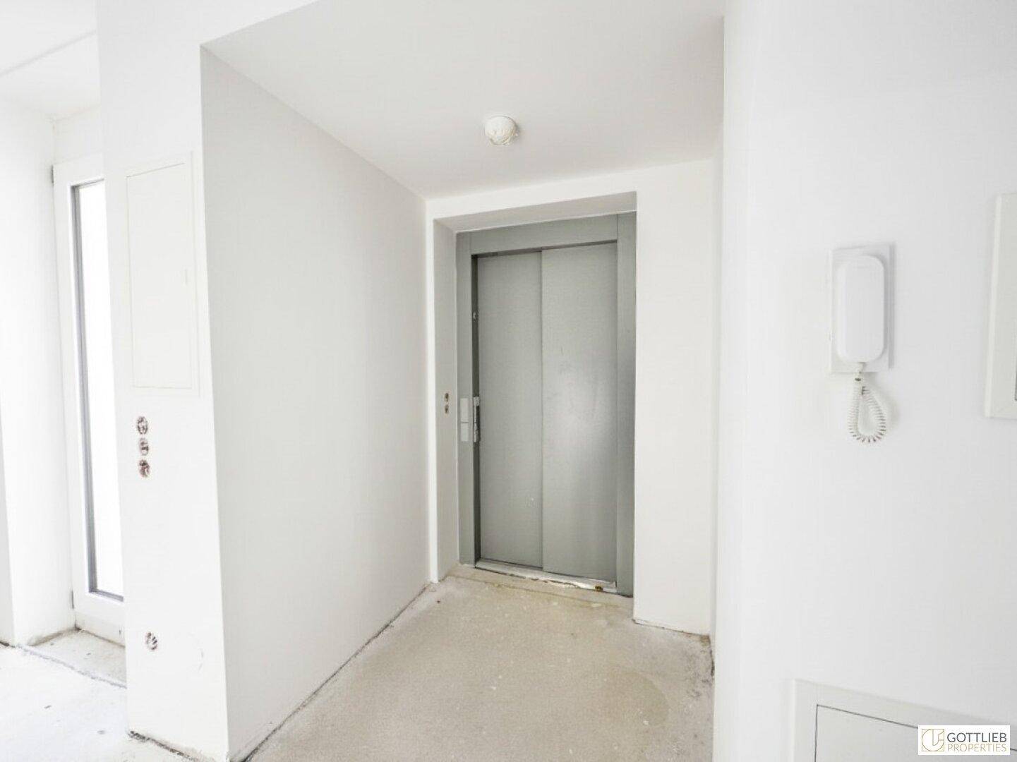Moderner Flur mit Aufzugzugang und Gegensprechanlage, bietet Komfort und Barrierefreiheit.