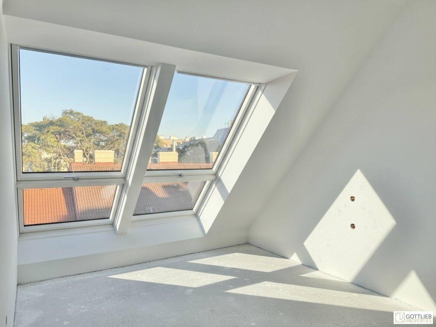 Helles Schlafzimmer im Dachgeschoss mit schrägen Wänden und zwei großen Dachfenstern.