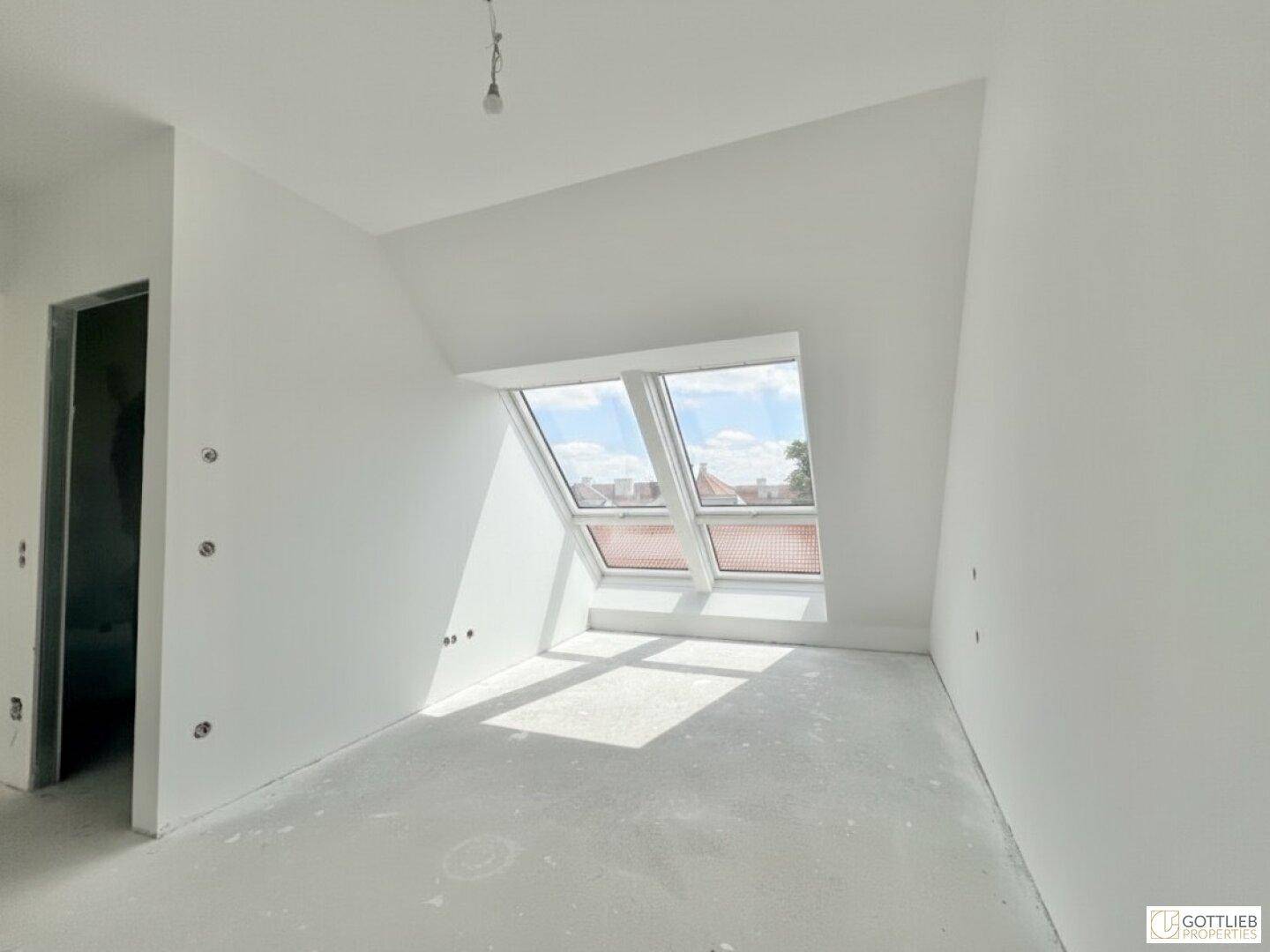 Heller Dachgeschossraum mit schrägen Wänden und zwei Dachfenstern, ideal als Kinderzimmer.