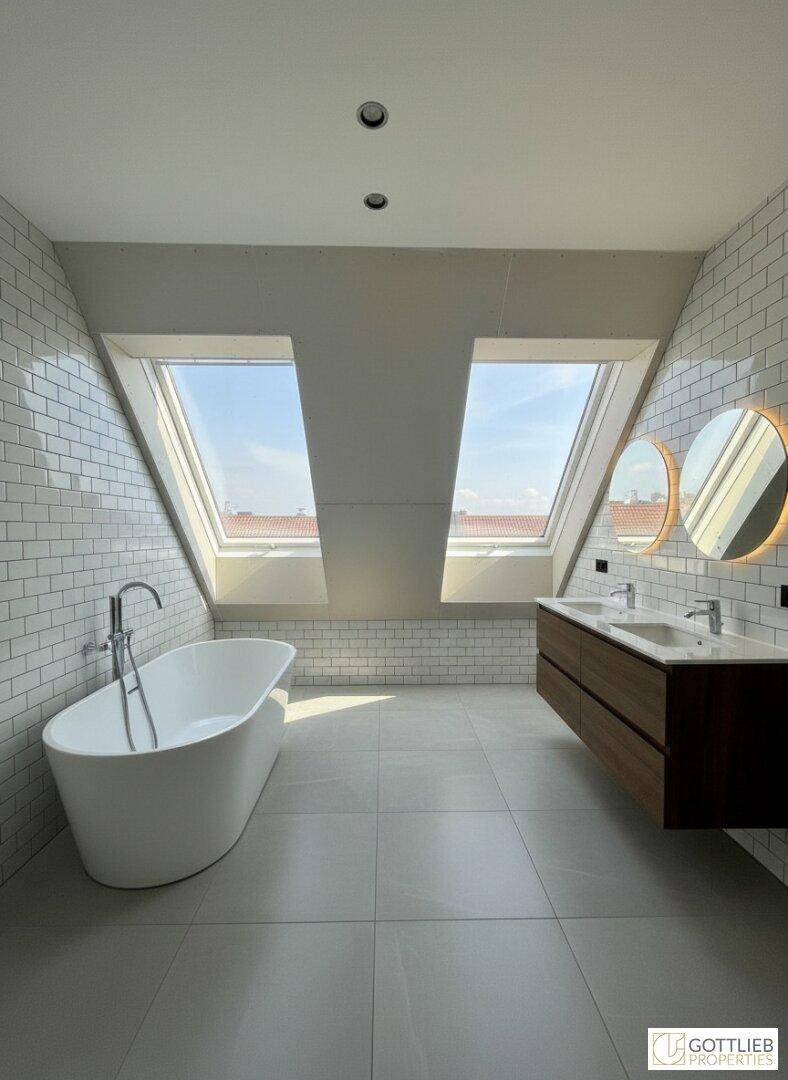 Modernes Badezimmer mit freistehender Badewanne, Doppelwaschbecken und großen Dachfenstern.