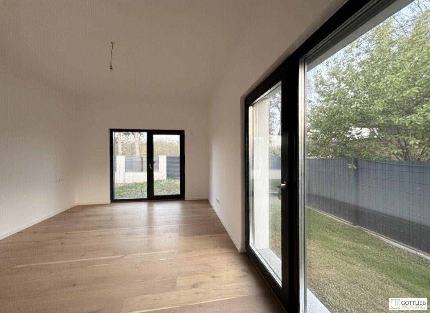 Geräumiges Schlafzimmer mit Parkettboden und Blick ins Grüne durch die großen Fenster.