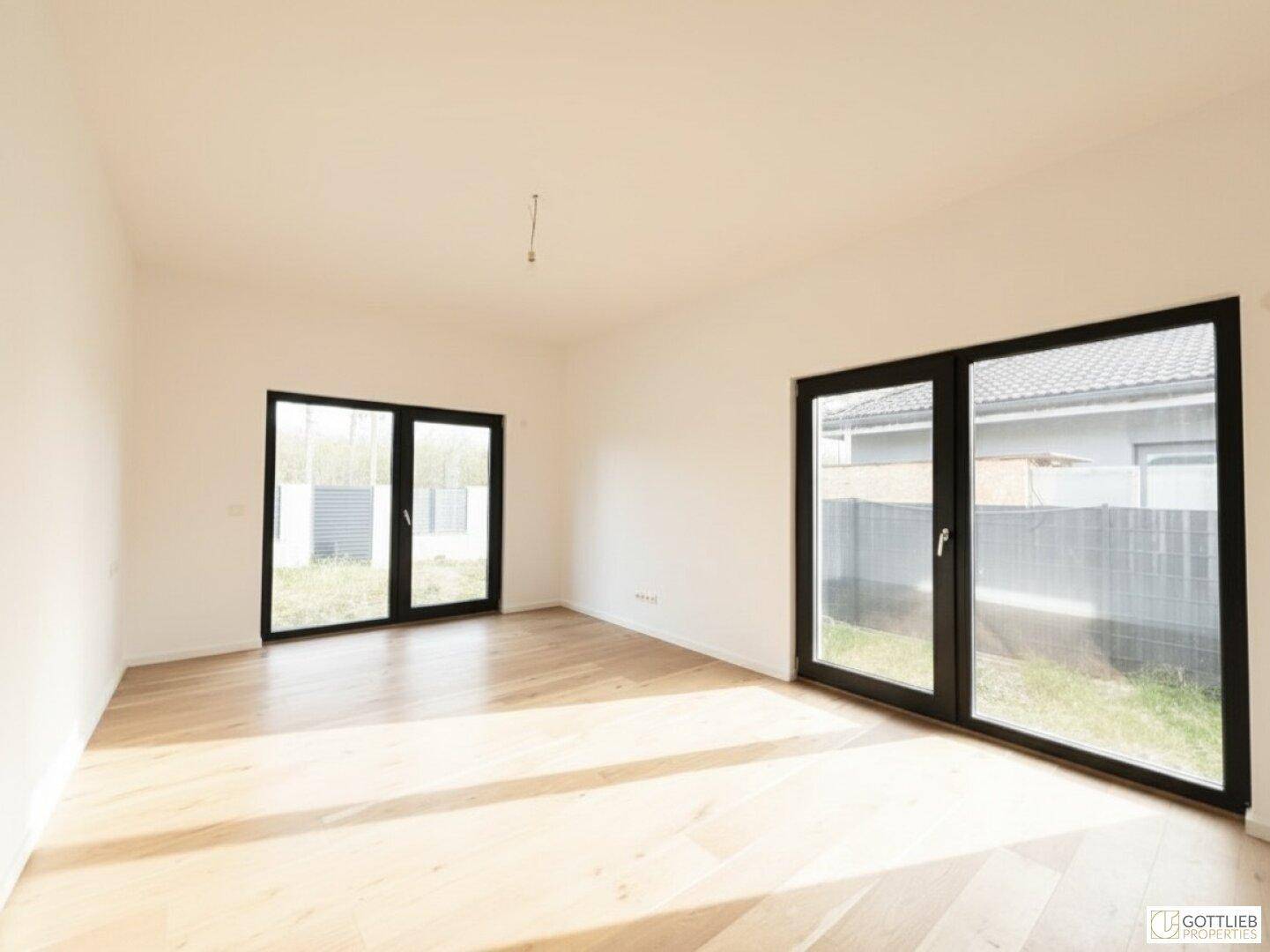 Helles Schlafzimmer mit Holzboden und großen Fenstern, die den Raum mit Tageslicht füllen.
