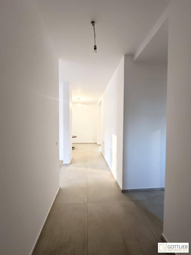 Langer, heller Flur mit Fliesenboden und klaren Linien, der die Räume miteinander verbindet.