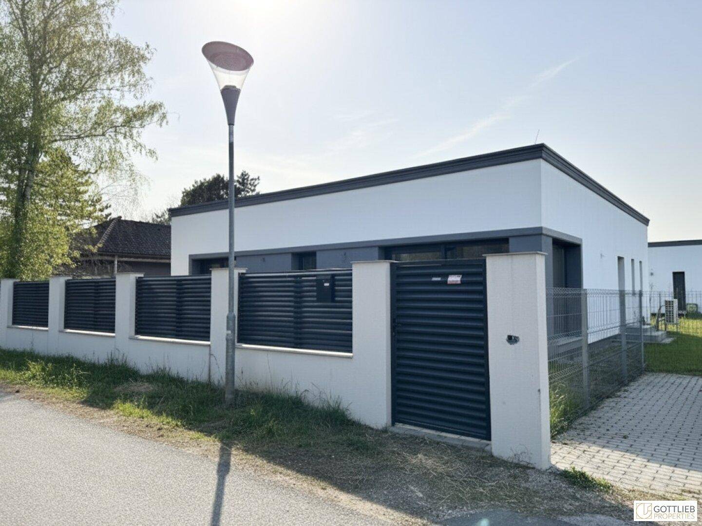 Außenansicht des Hauses von der Straße mit modernem Zaun und Einfahrtstor.