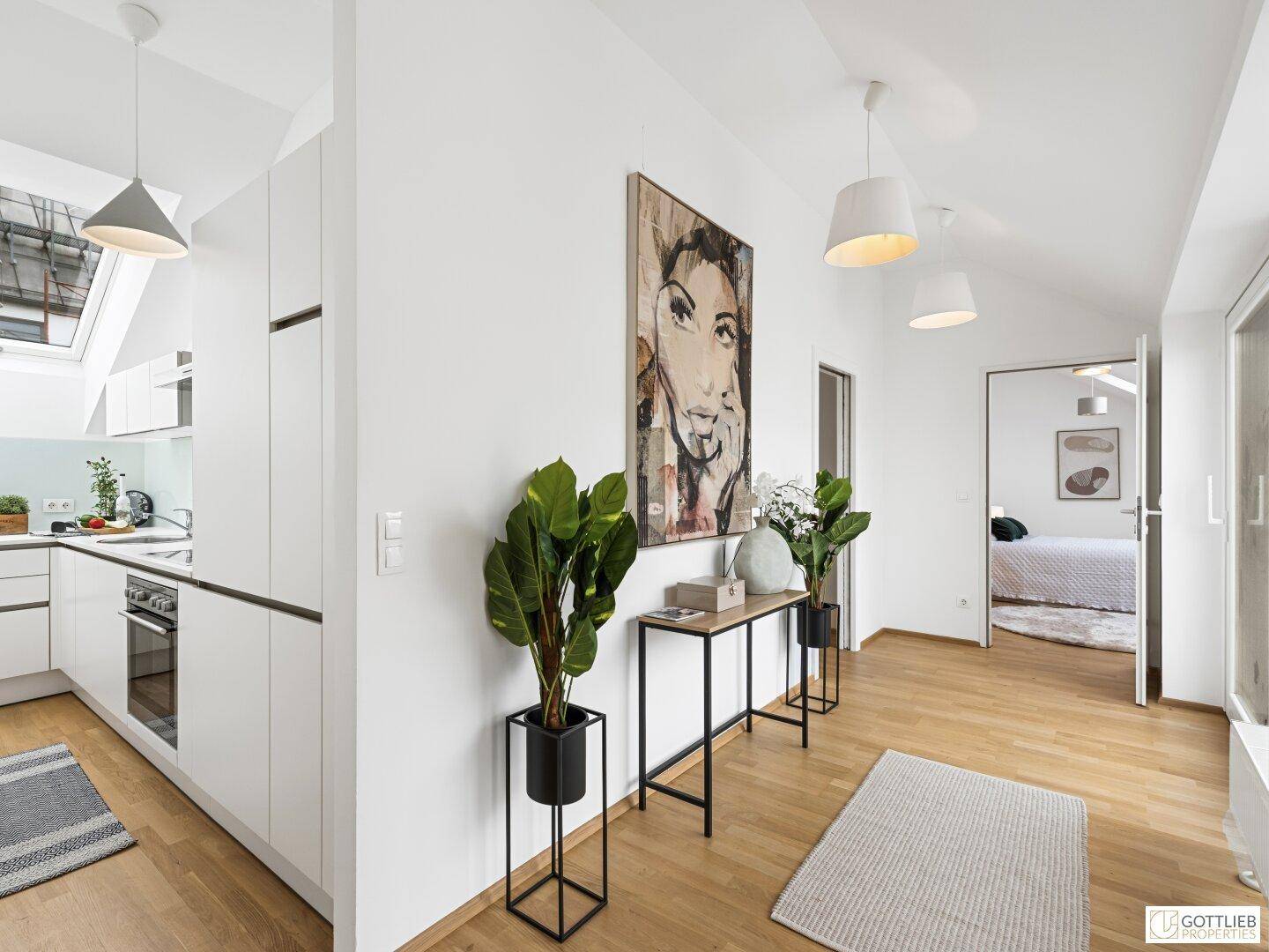 Moderner Flur mit Holzboden, dekorativen Pflanzen und offenem Übergang zu Küche und Schlafzimmer.