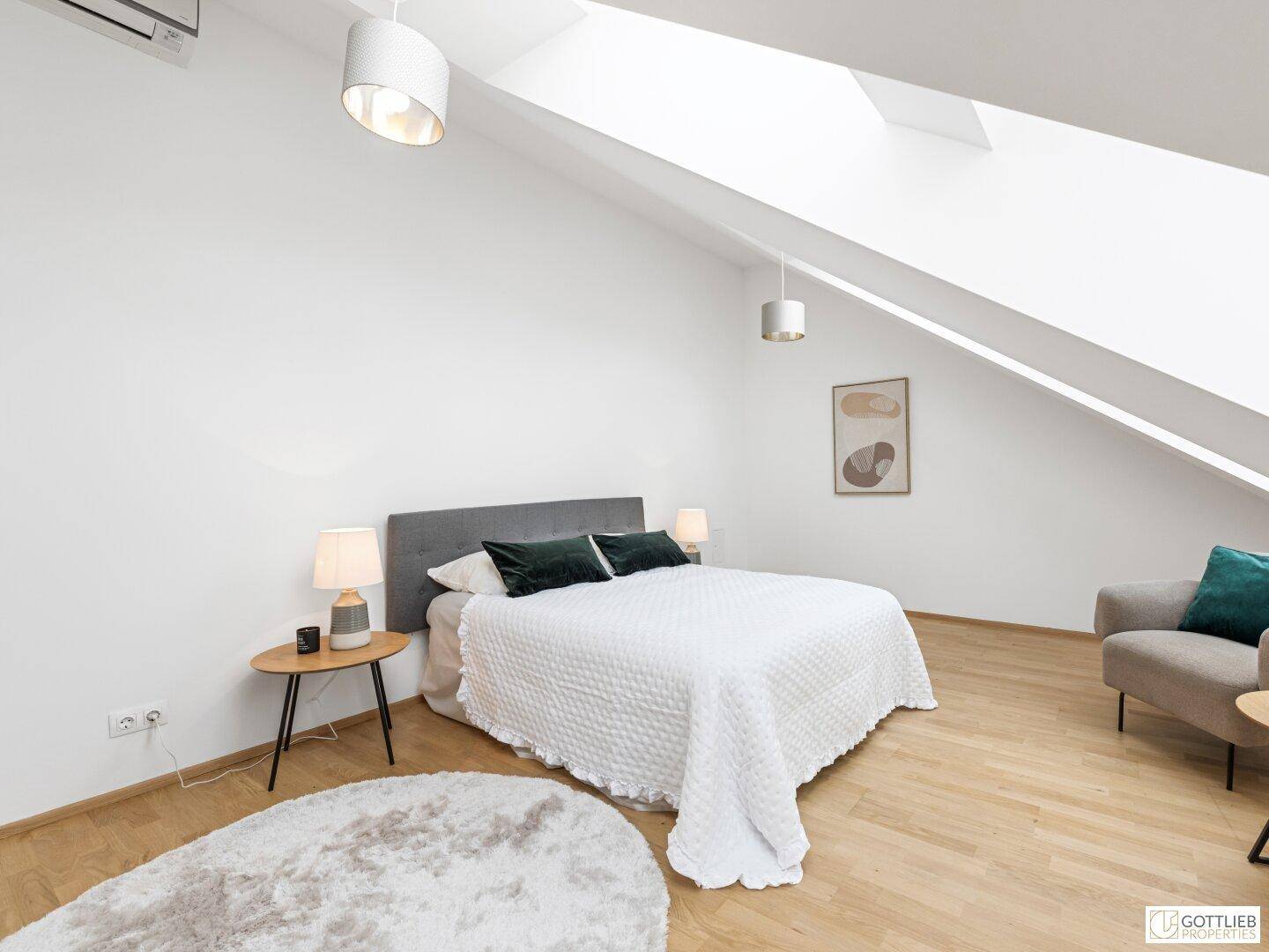 Gemütliches Schlafzimmer mit Doppelbett, schräger Decke und viel Tageslicht durch das Dachfenster.