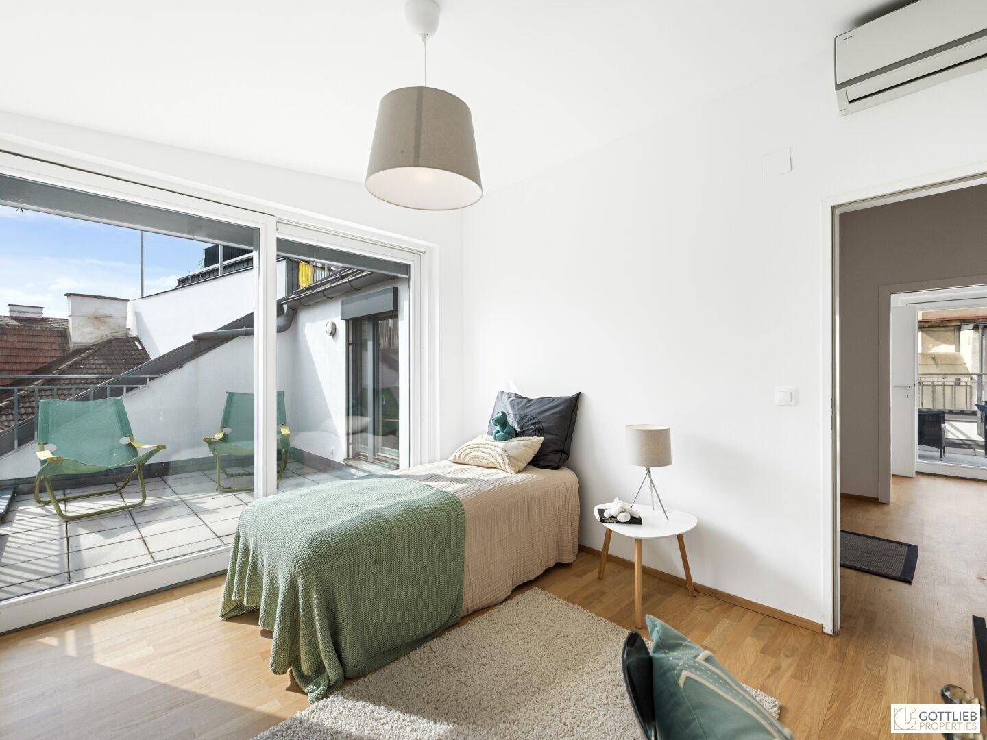 Lichtdurchflutetes Schlafzimmer mit Einzelbett und großem Fenster, das auf den Balkon führt.