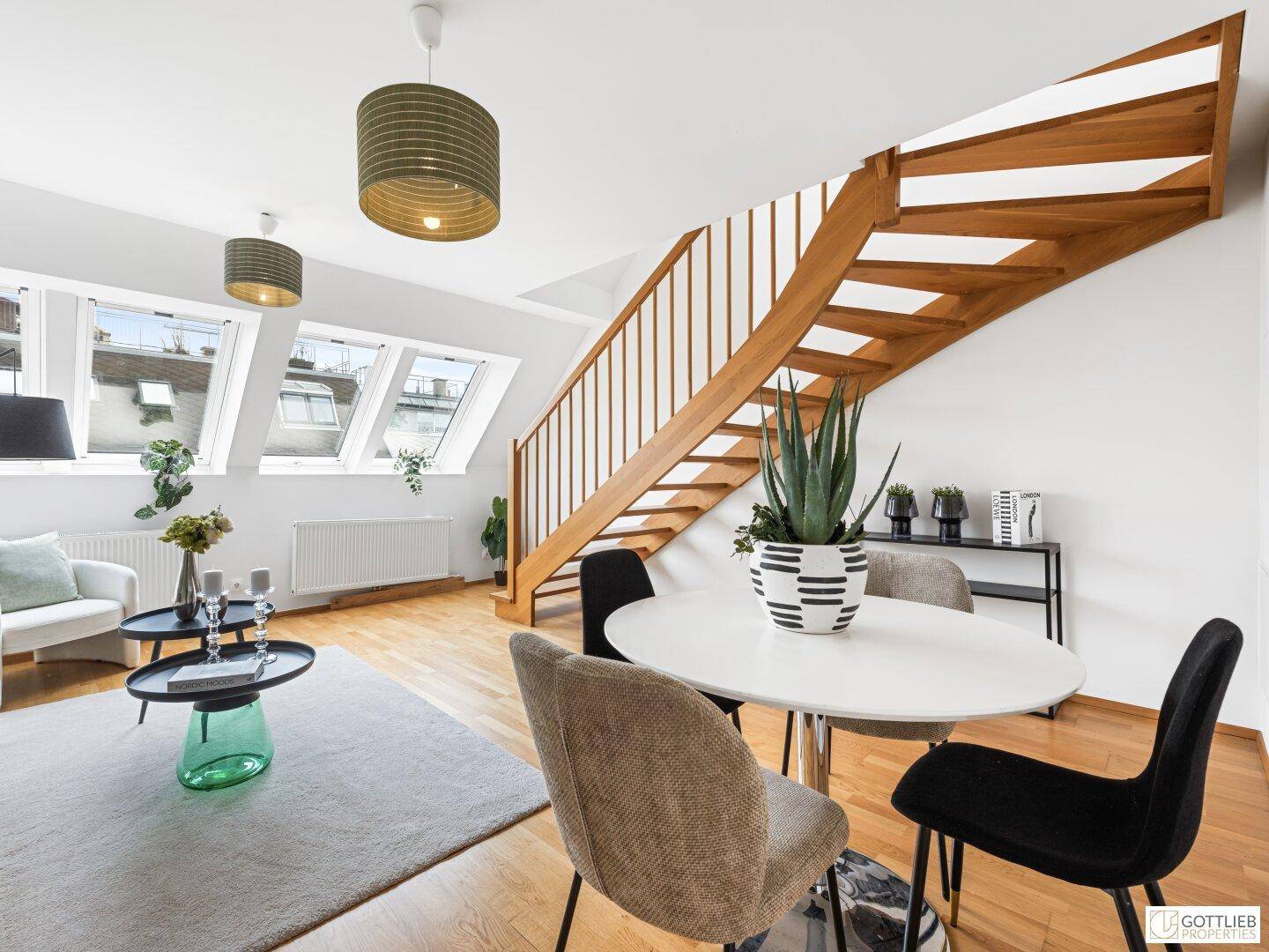Geräumiger Wohn- und Essbereich mit geschwungener Holztreppe und viel Tageslicht durch die Dachfenster.