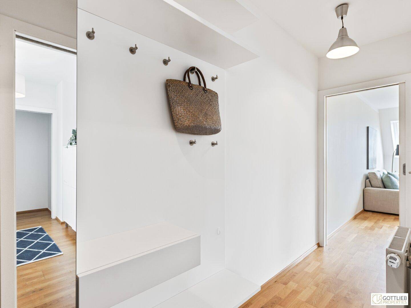 Heller Flur mit Garderobe, Spiegel und Holzfußboden, der zu den weiteren Räumen führt.