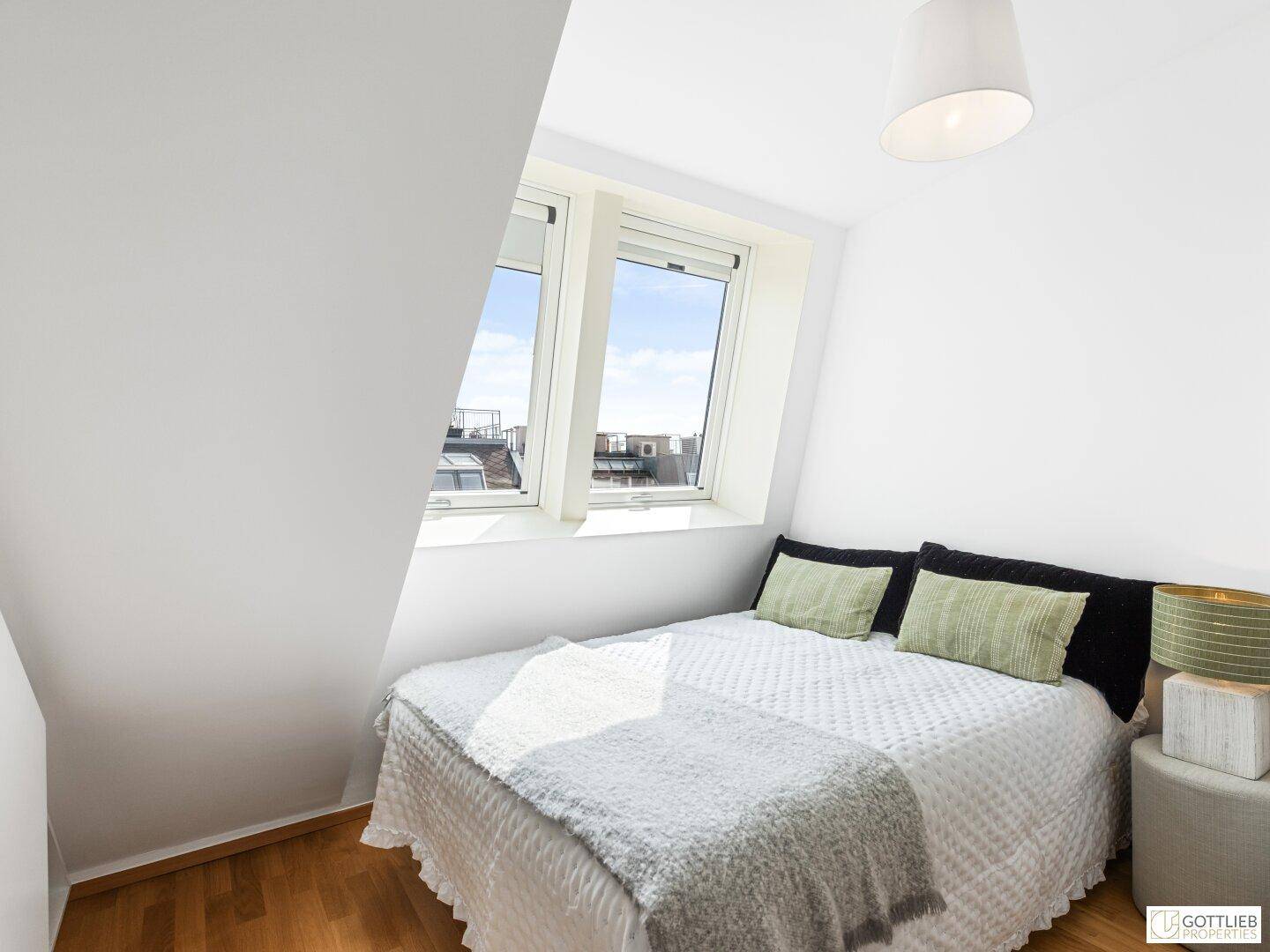 Helles Schlafzimmer mit Doppelbett, Dachschräge und zwei Dachfenstern, die eine angenehme Atmosphäre schaffen.