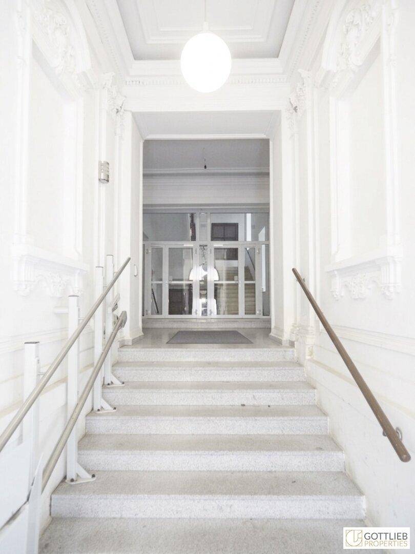 Repräsentativer Eingangsbereich mit Marmortreppe, Stuckdecke und klassischer Architektur.