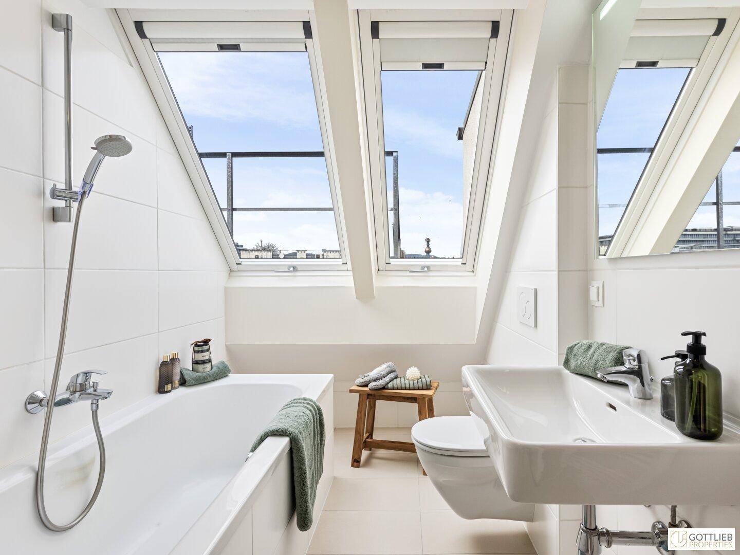 Modernes Badezimmer mit Badewanne, Dusche, WC und Waschbecken, hell durch die Dachfenster.
