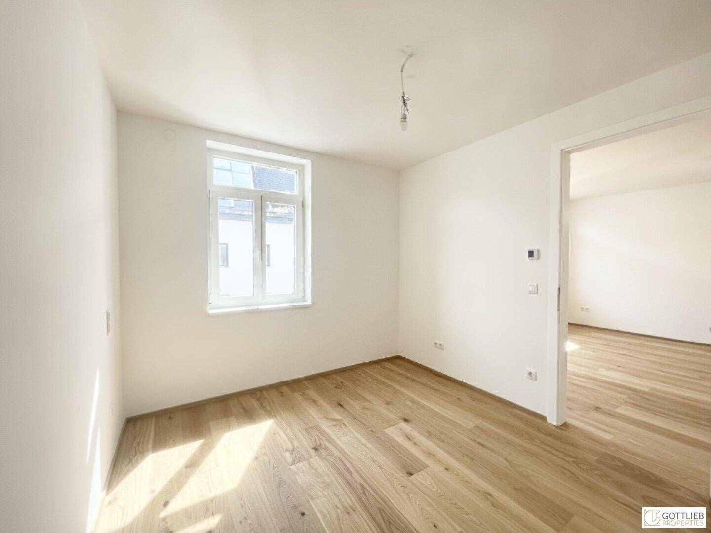 Leerer Raum mit hellem Holzboden und weiß gestrichenen Wänden, bereit zur individuellen Gestaltung.