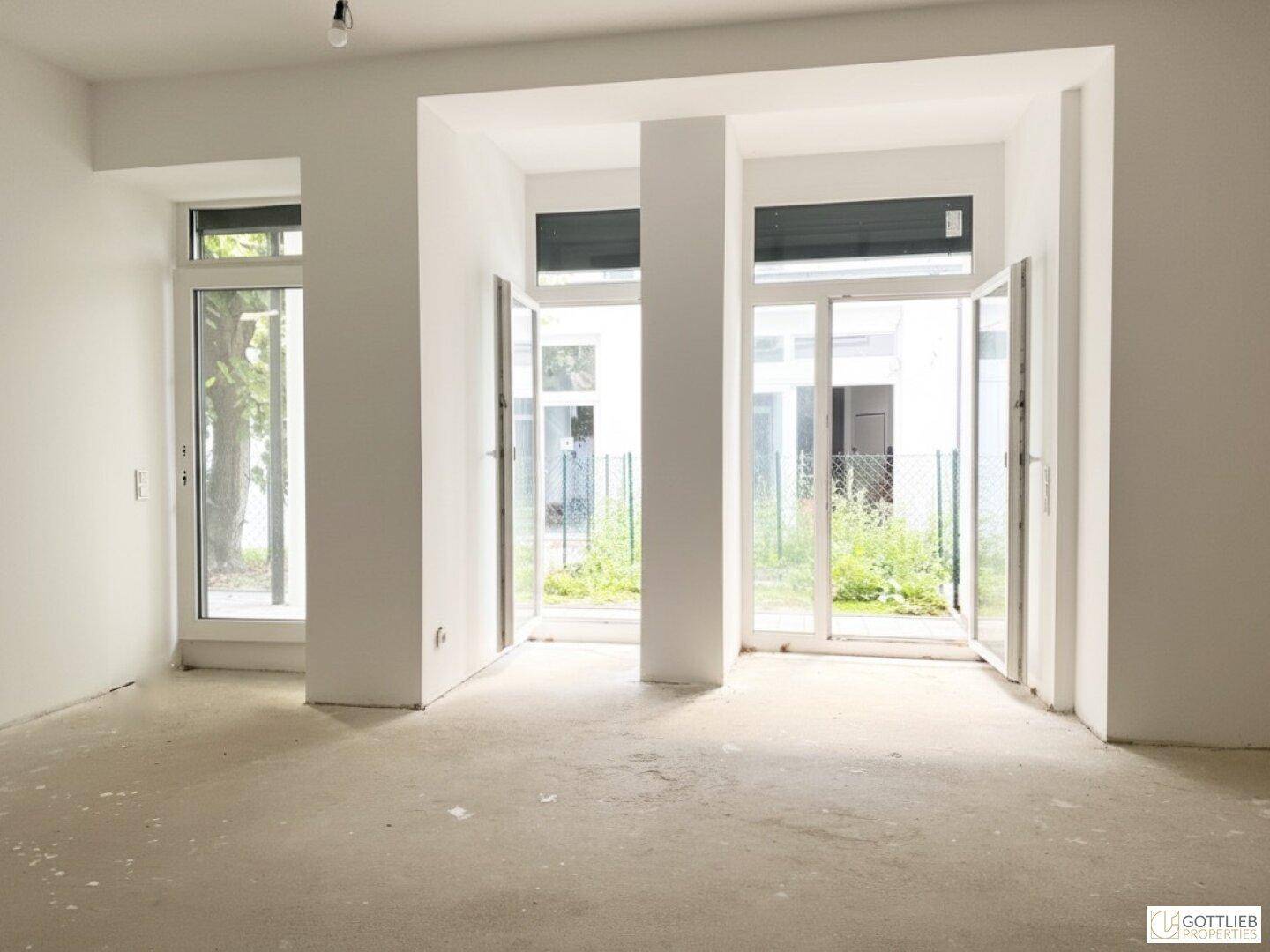 Geräumiger, heller Raum mit mehreren Fenstertüren, die viel Tageslicht hereinlassen.