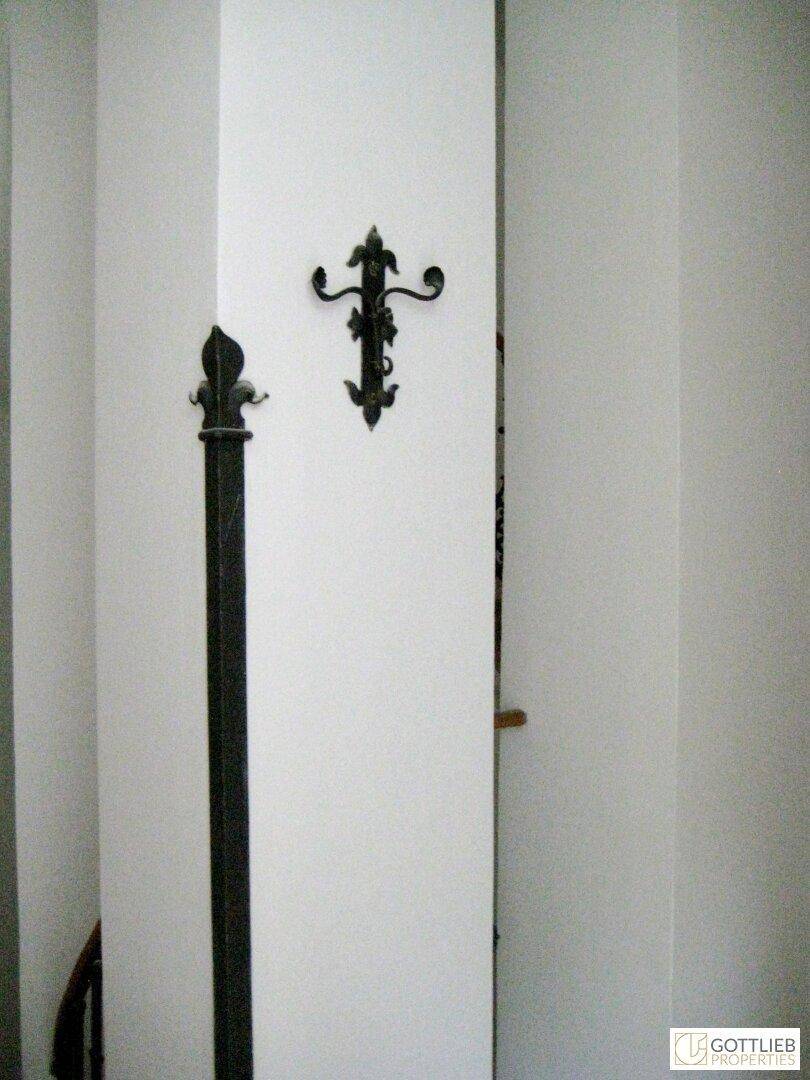 Detailansicht einer weißen Wand mit einem dekorativen schmiedeeisernen Wandleuchter.