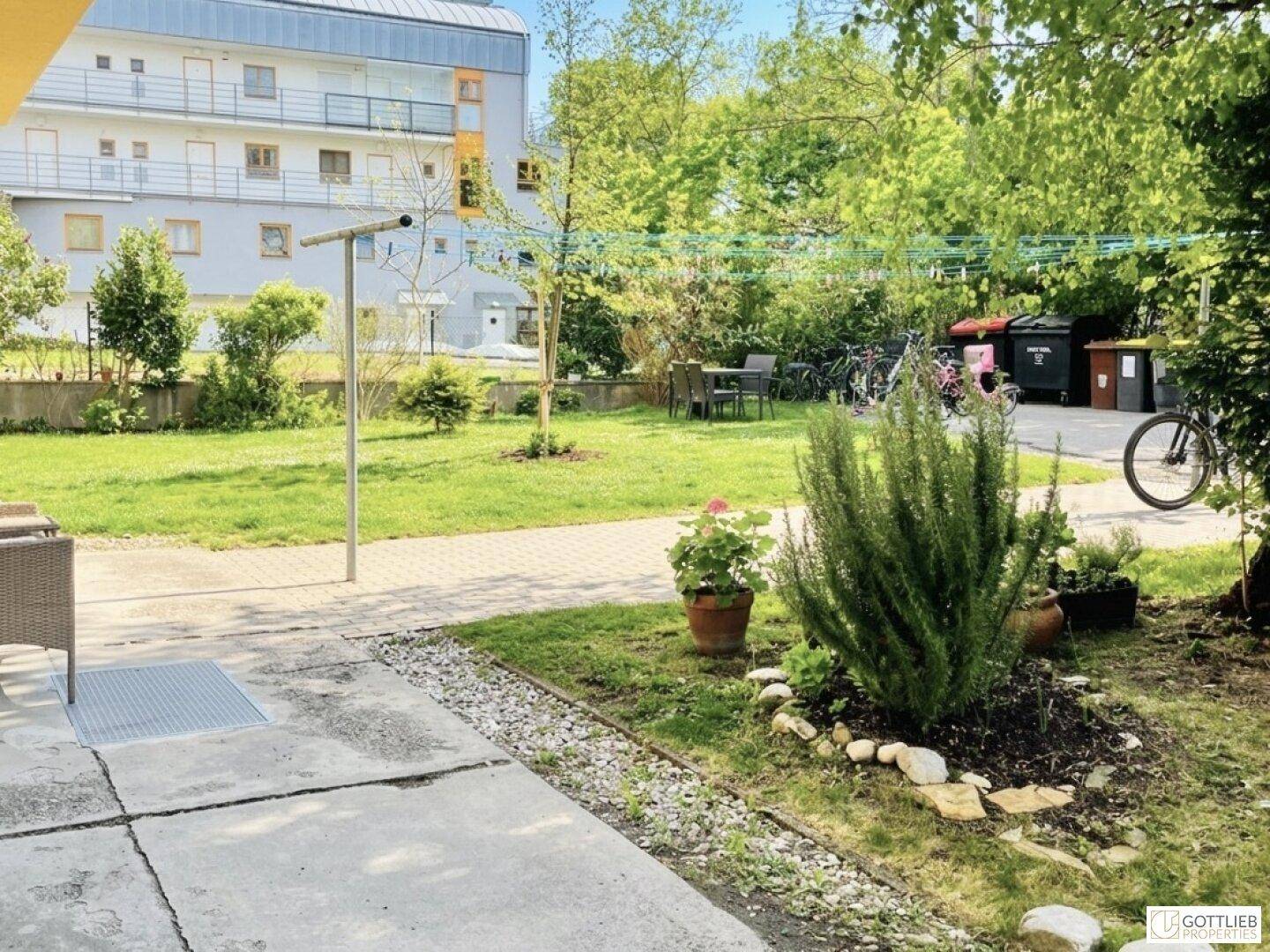 Gepflegter Gemeinschaftsgarten mit Rasenfläche, Sitzgelegenheiten und Wäscheleinen.