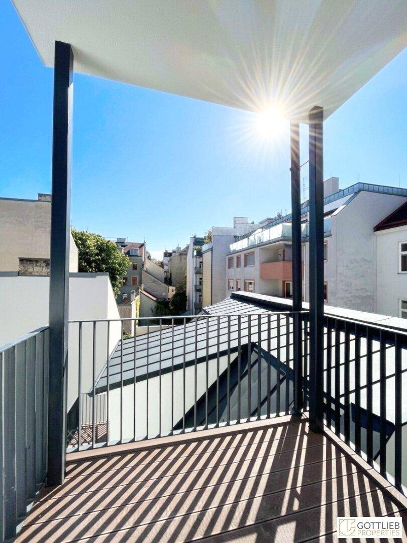 Sonniger Balkon mit Holzboden und Blick auf die Stadt, ideal für entspannte Stunden im Freien.