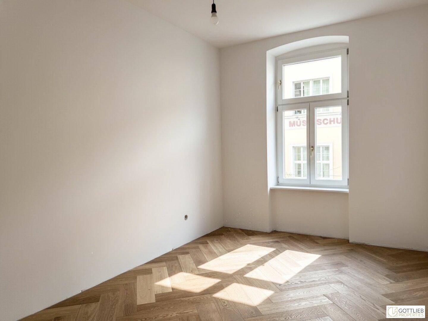 Heller Raum mit Fischgrätparkett und einem hohen Fenster, bietet viel Tageslicht und Ruhe.