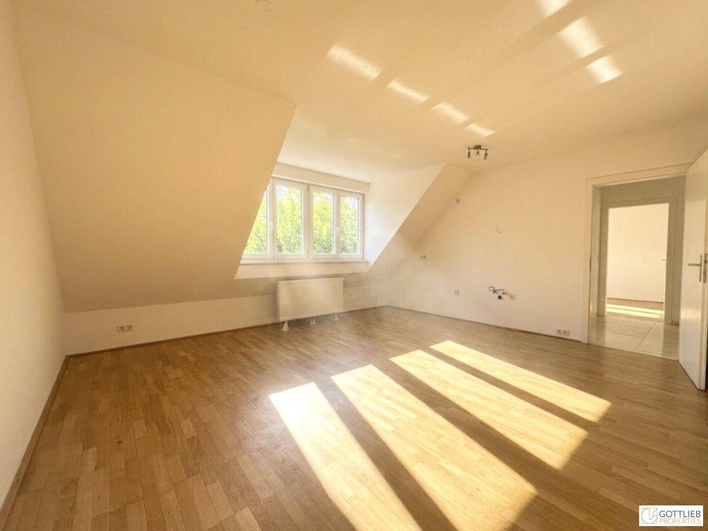 Lichtdurchflutetes Dachgeschosszimmer mit Holzboden und schrägen Wänden, ideal als Schlafzimmer.