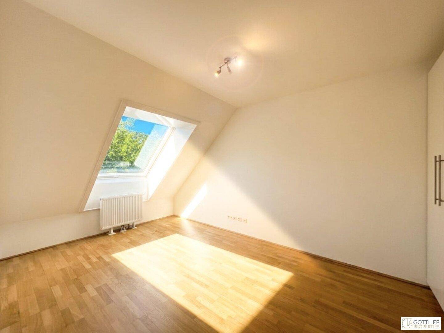 Gemütliches Dachgeschosszimmer mit Holzboden und Dachfenster, ideal für natürliches Licht.