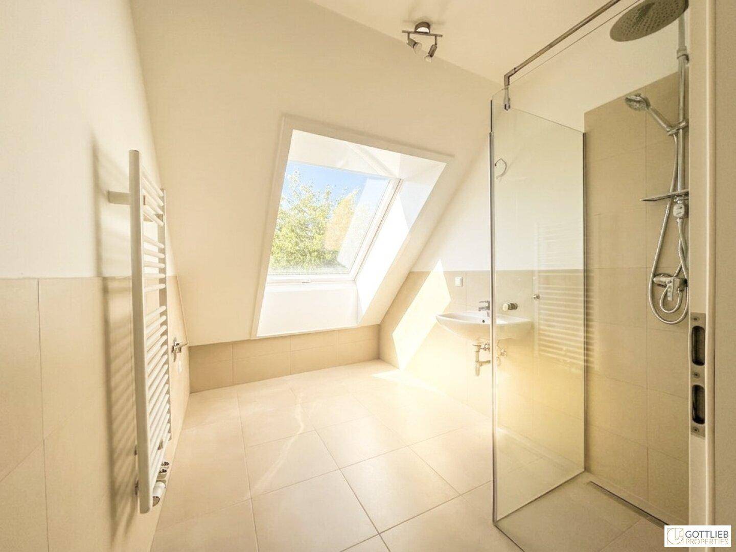 Modernes Badezimmer im Dachgeschoss mit begehbarer Dusche, Fliesenboden und Dachfenster.