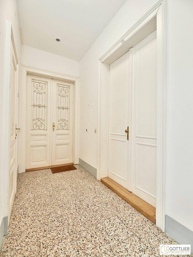 Heller Flur mit Terrazzoboden und eleganten weißen Doppeltüren, die den Eingangsbereich prägen.