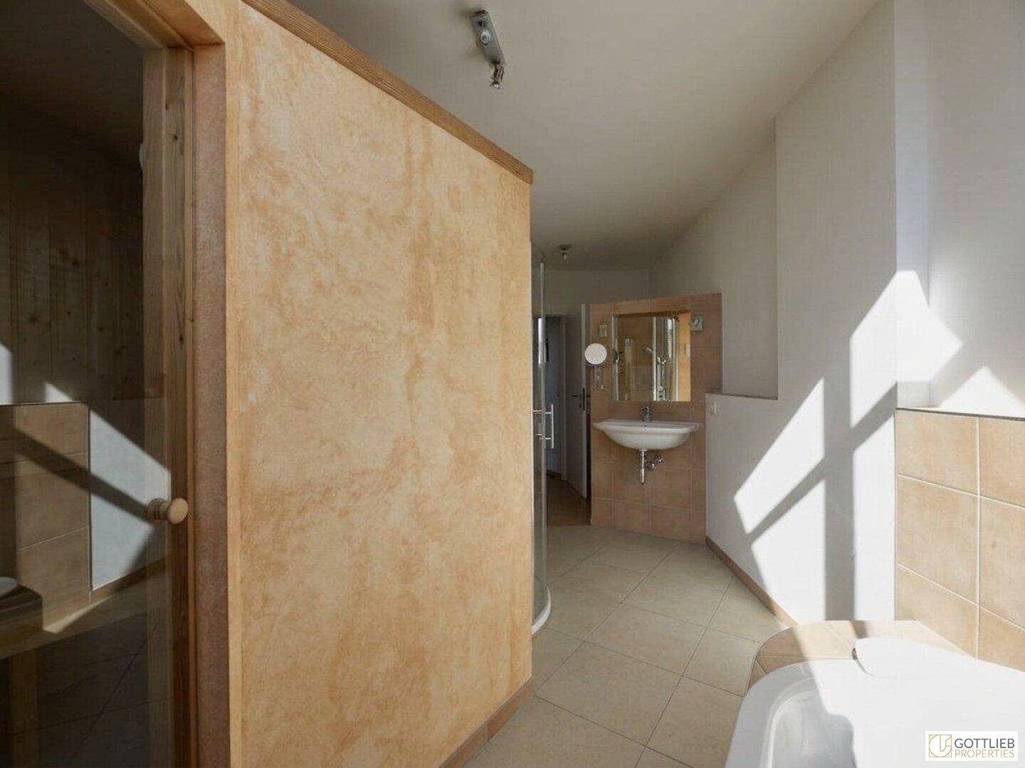 Modernes Badezimmer mit integrierter Sauna und hellem Fliesenboden.
