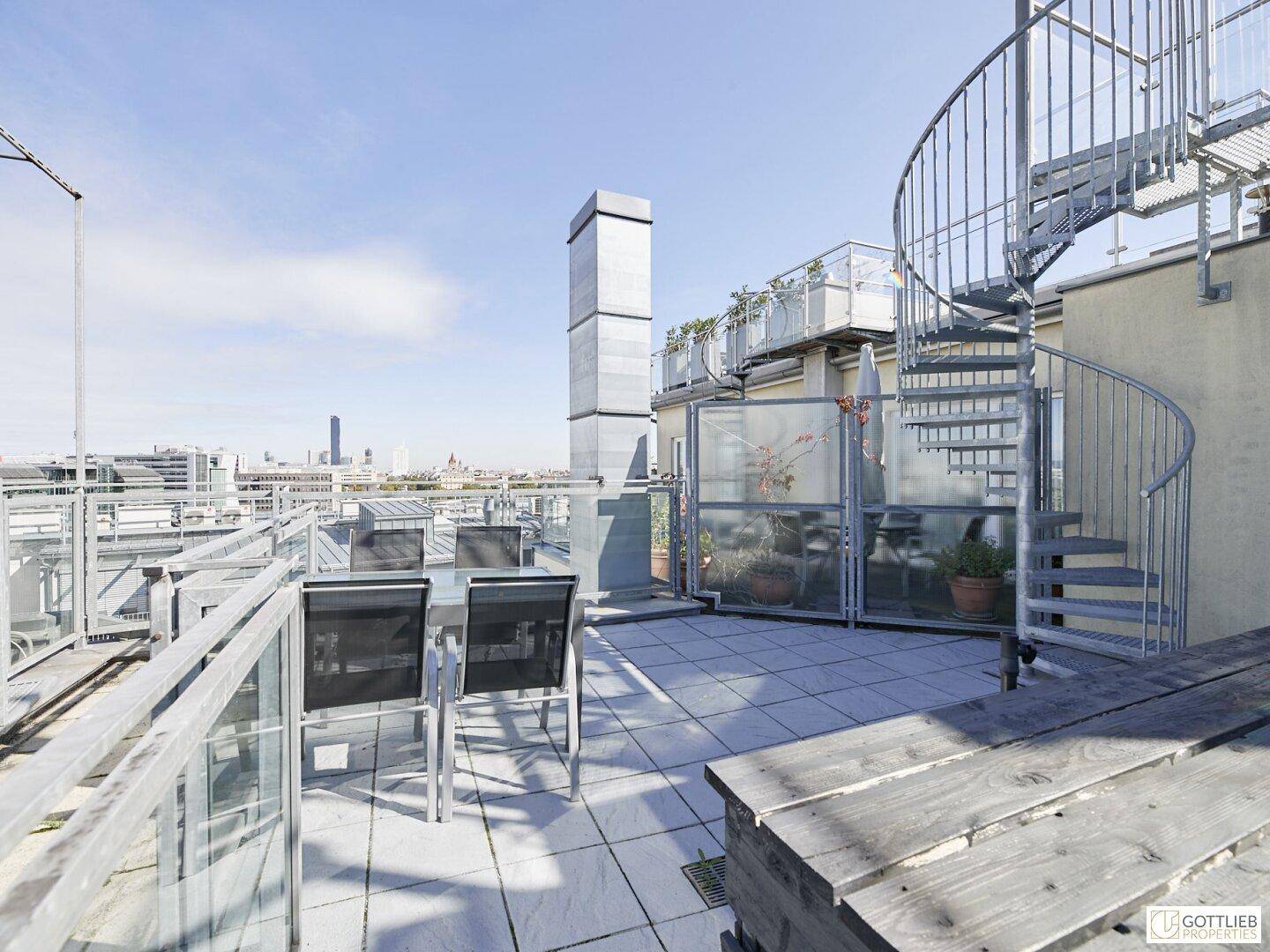 Dachterrasse mit Sitzgelegenheiten, Wendeltreppe und Panoramablick über die Stadt.